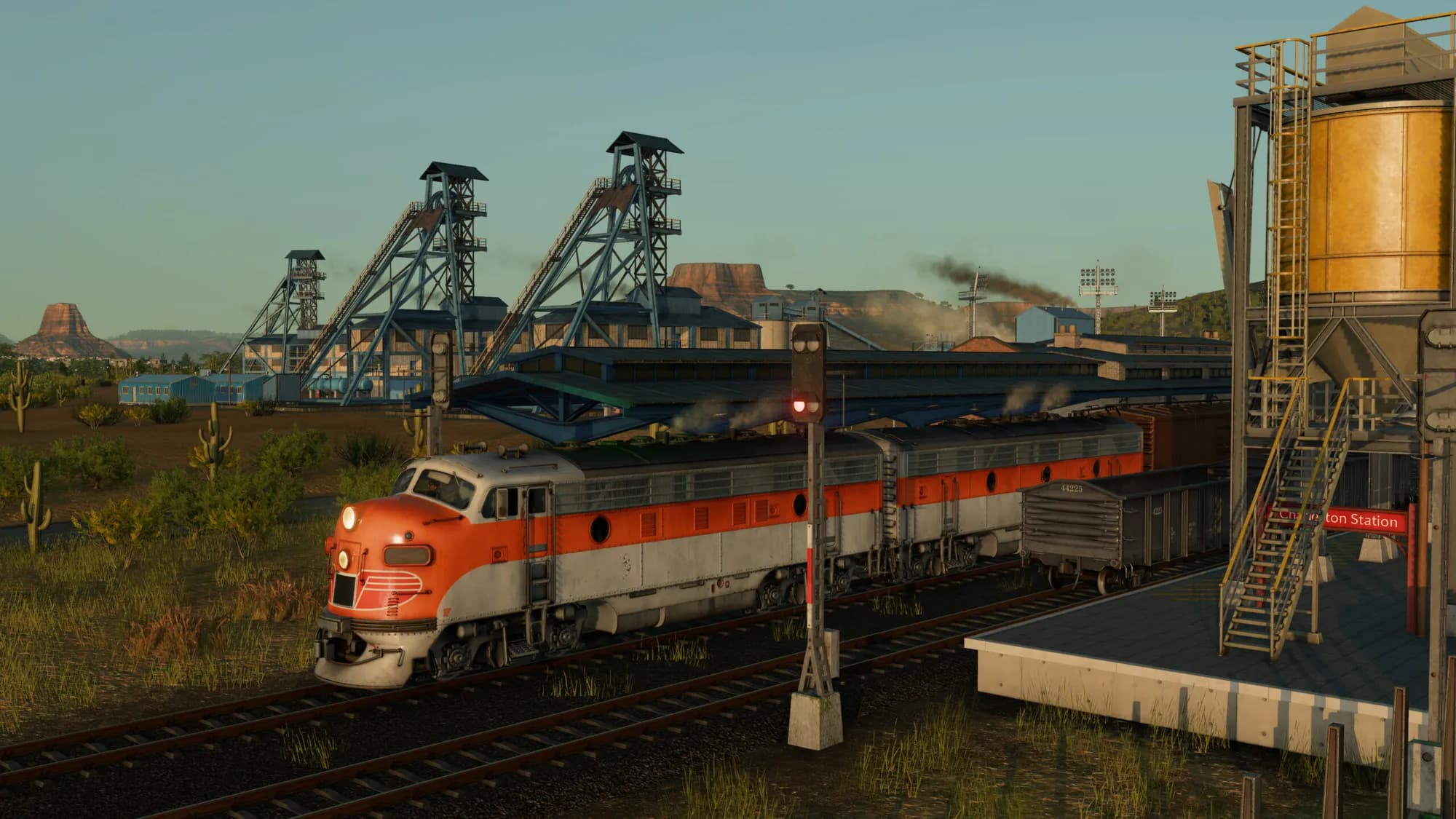 Locomotiva laranja e prateada a sair de uma mina no deserto, no Transport Fever 3